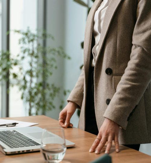 A professional businesswoman in a stylish office environment with a laptop and notes.